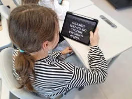 Ученица открывает онлайн-тетрадь по теории русского языка на планшете